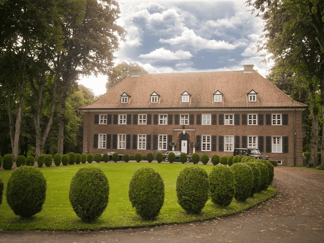Backstein-Herrenhaus mit weiß gefassten Fenstern hinter einer Buchsbaum-Rabatte — das Büro von Heidemann & Elbe in Neumünster